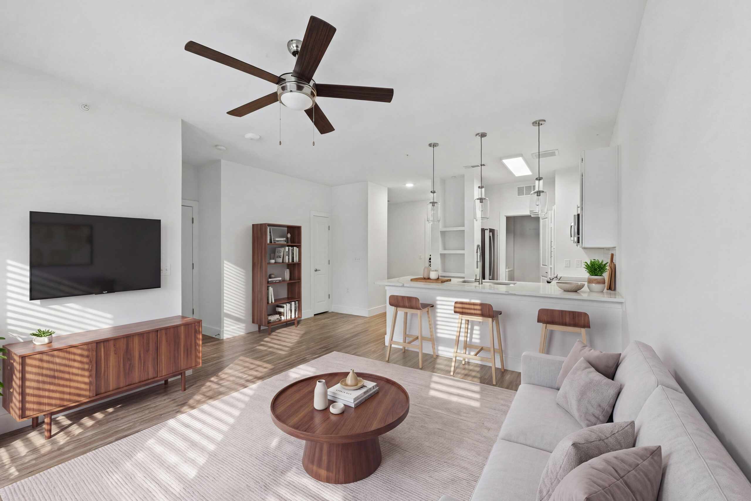 Bright open-concept living room and kitchen at Embree Hill with wood-style flooring, a breakfast bar, and pendant lighting.