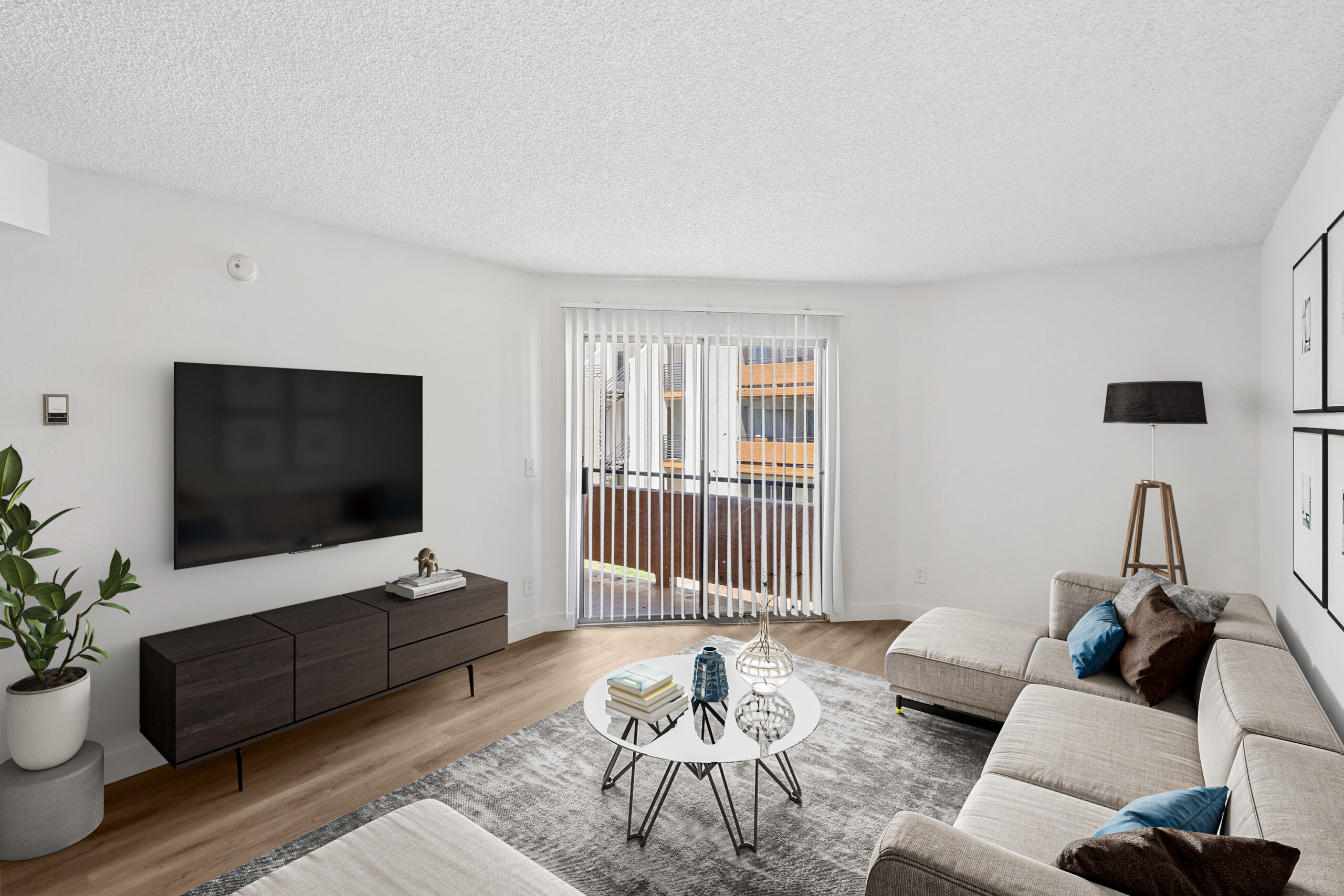 Spacious Meadow Glen living room with wood-style flooring, modern furnishings, and sliding glass doors leading to a private balcony.