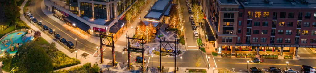 aerial view at dusk of cars on the street in front of apartments and store fronts