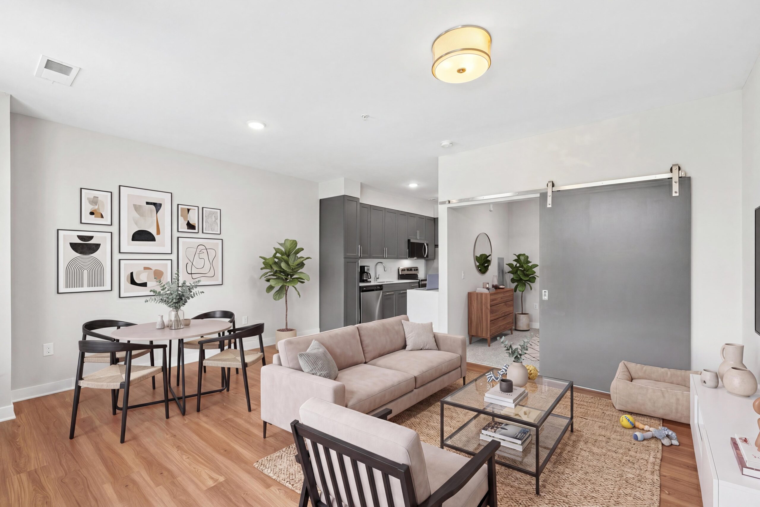 Spacious and stylish living room with interior bedroom with barn door closure and modern living room and dining furniture, artwork, and open layout in Baltimore.