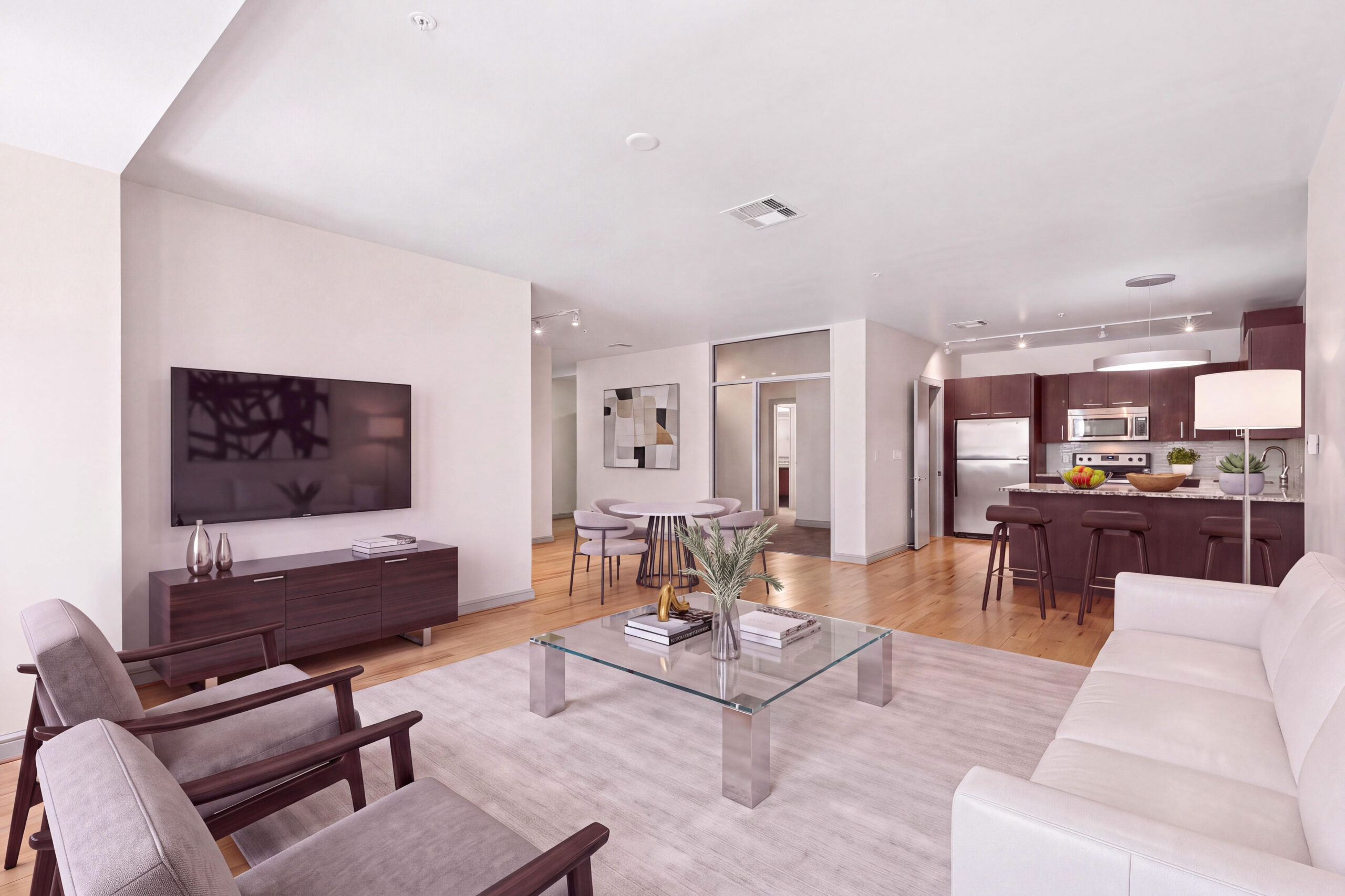 Living room with hardwood flooring, living room sofa and chair set with a mounted television.