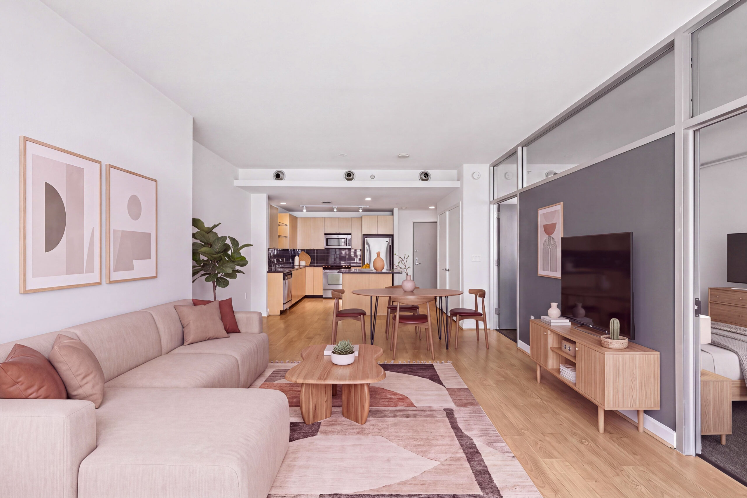 Modern open-concept apartment with a spacious living room, dining area, wood-style flooring and kitchen with stainless steel appliances.