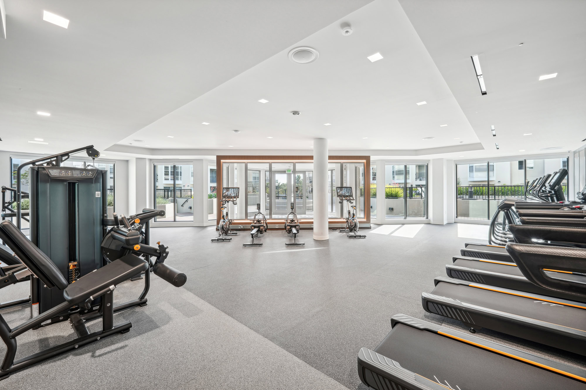 A fully equipped modern fitness center with glass windows at Bayside Village apartments in San Francisco