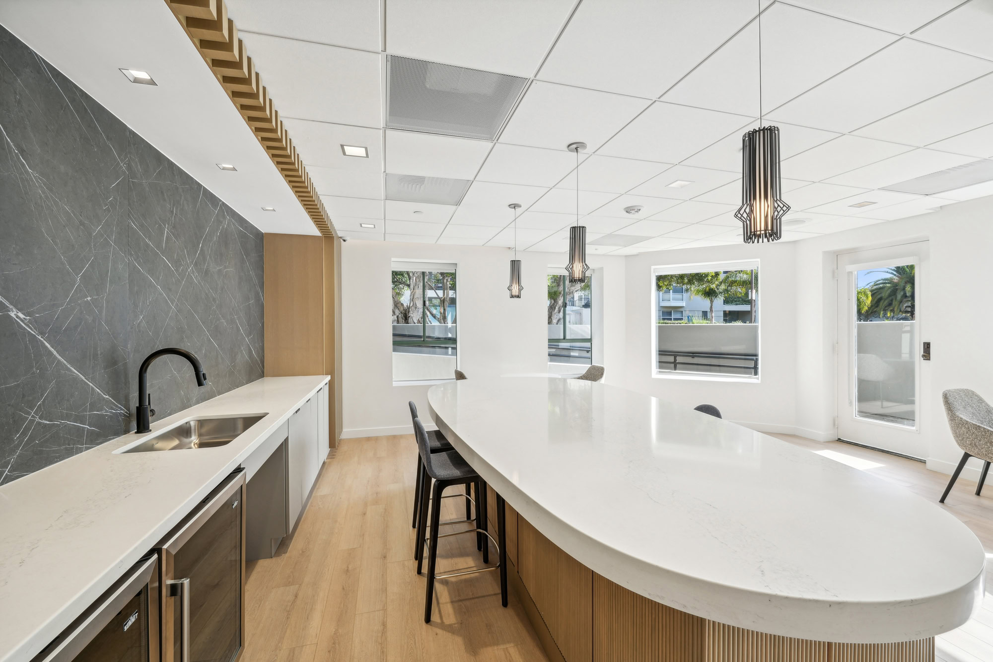 A fully equipped kitchen with an oval kitchen island and several windows in a lounge at Bayside Village apartments in San Francisco