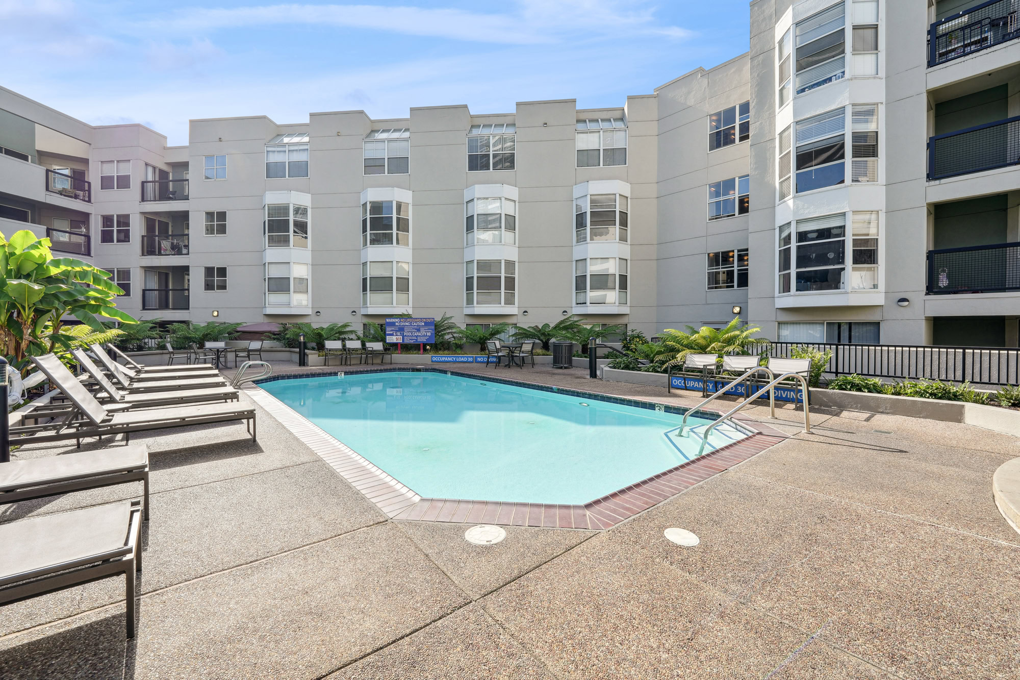 A medium sized regular pool with lounging chairs and benches, surrounded by Bayside Villages modern apartments in downtown San Francisco