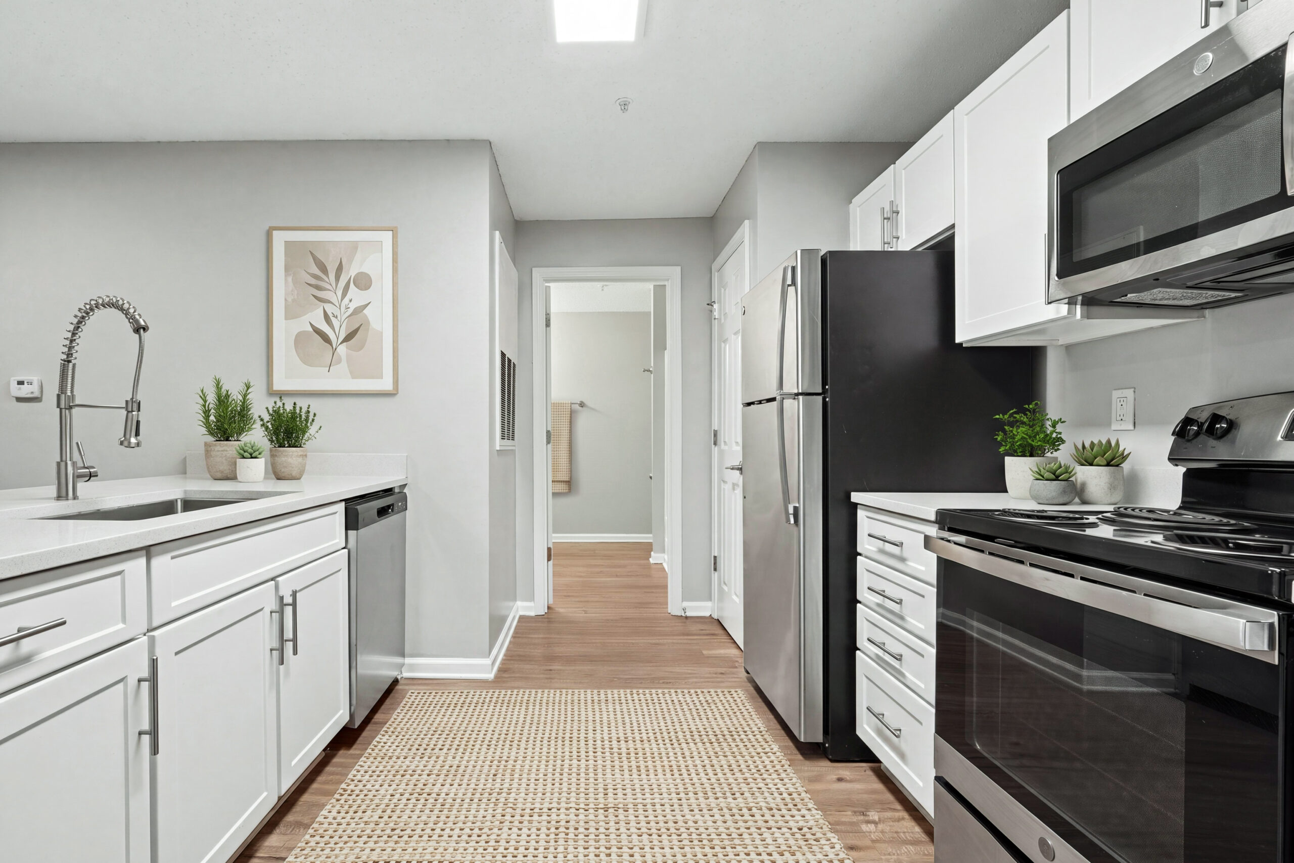 Modern kitchen with stainless steel appliances, plank flooring, and granite like countertops