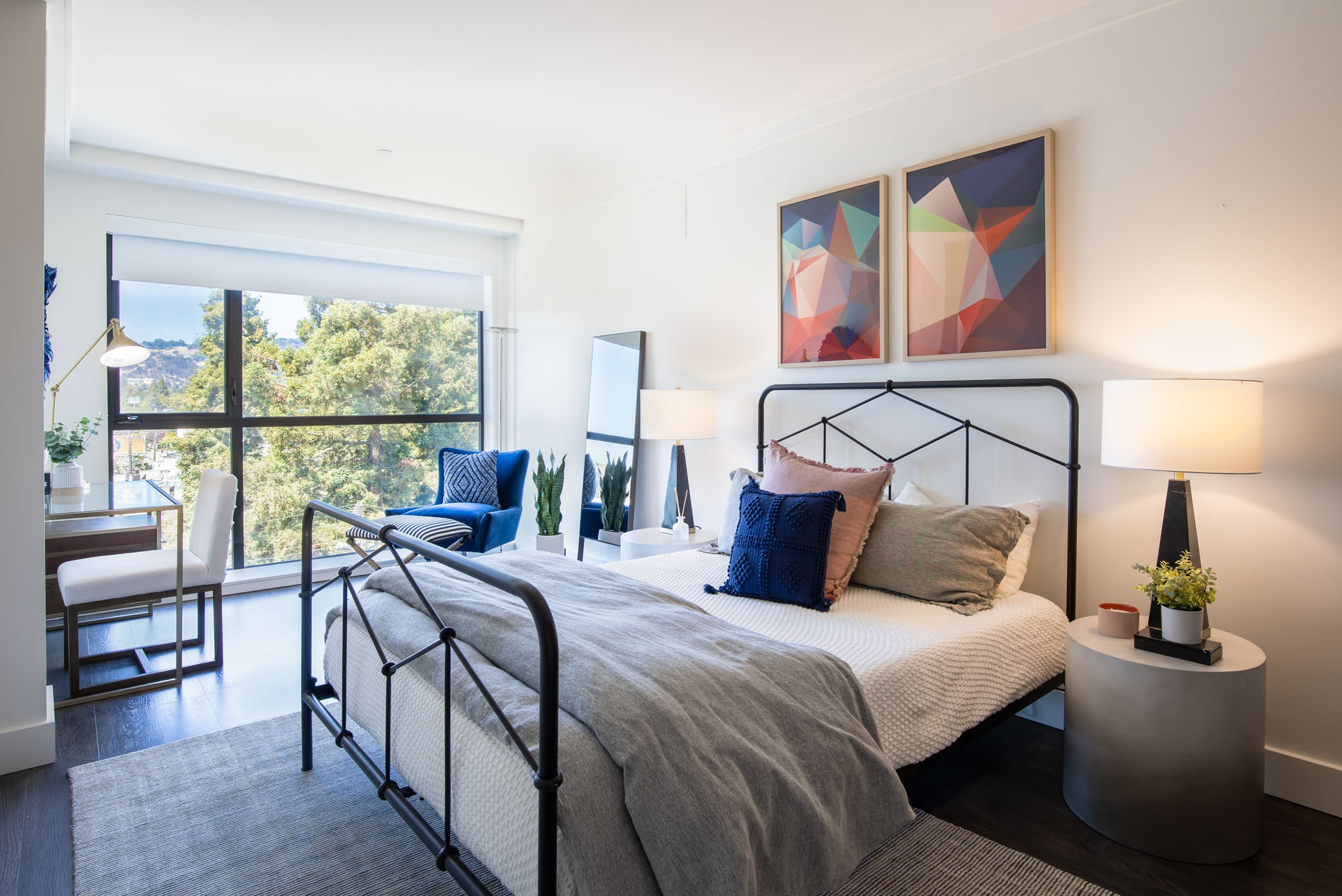 A bedroom with a work from home space and large window with city views at The logan, Temescal luxury apartments for rent