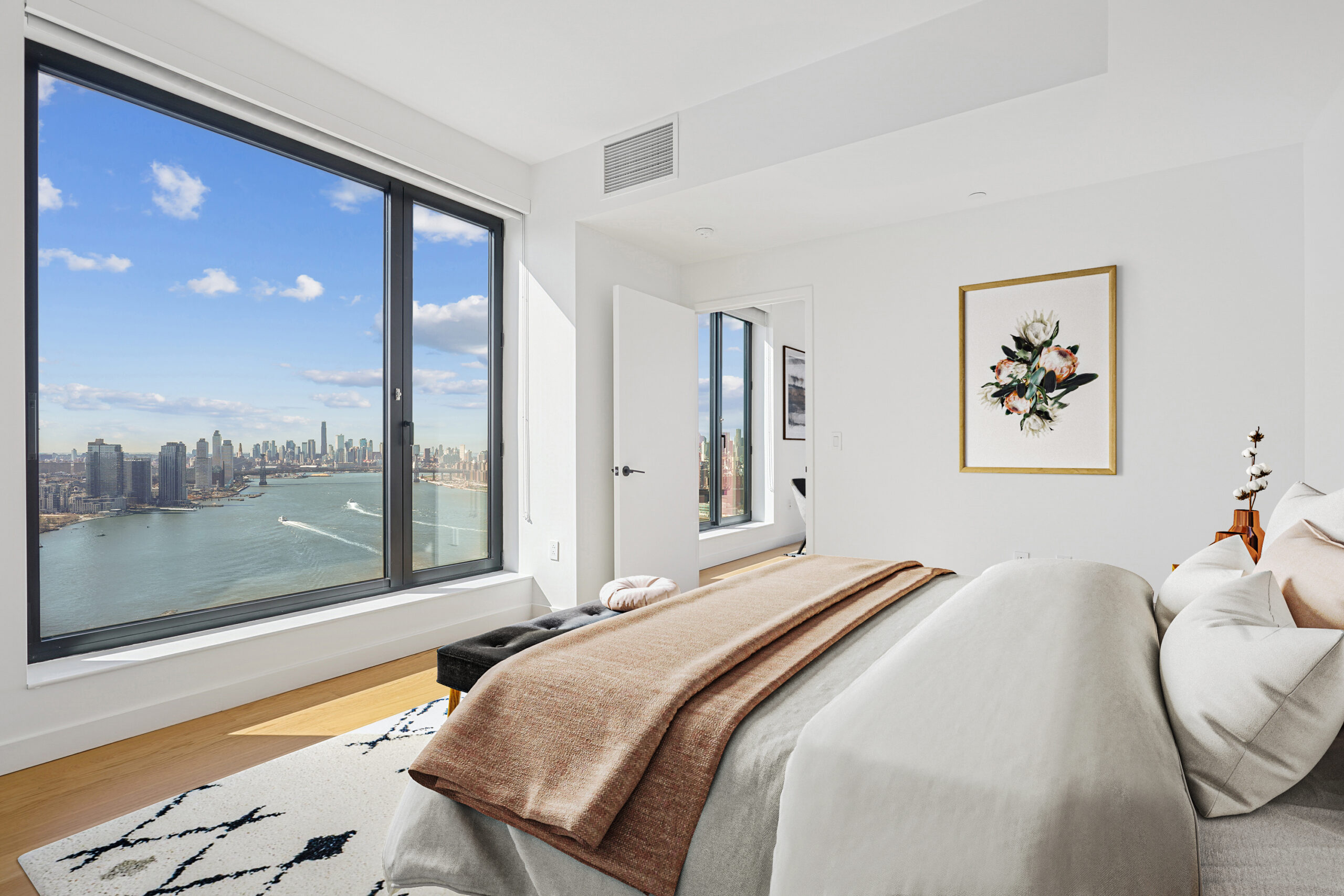 Spacious modern bedroom with views of the water and cityscape