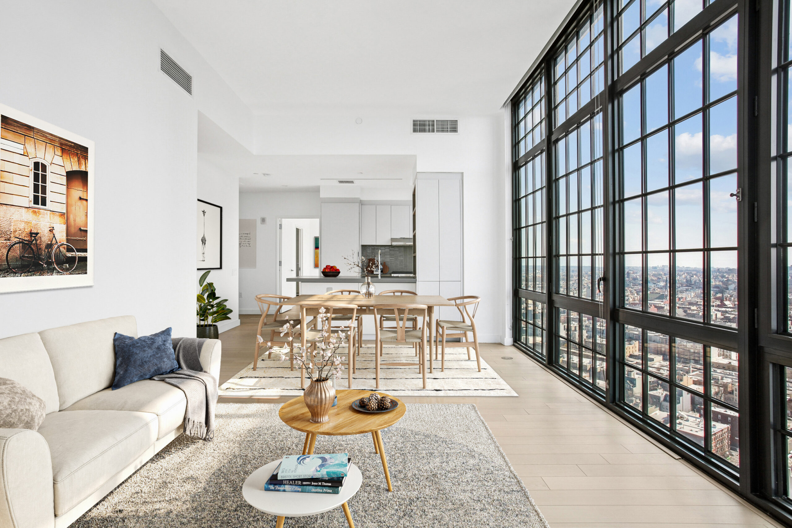 Spacious kitchen with island and built-in shelving and living area with generous floor-to-ceiling windows offering city views