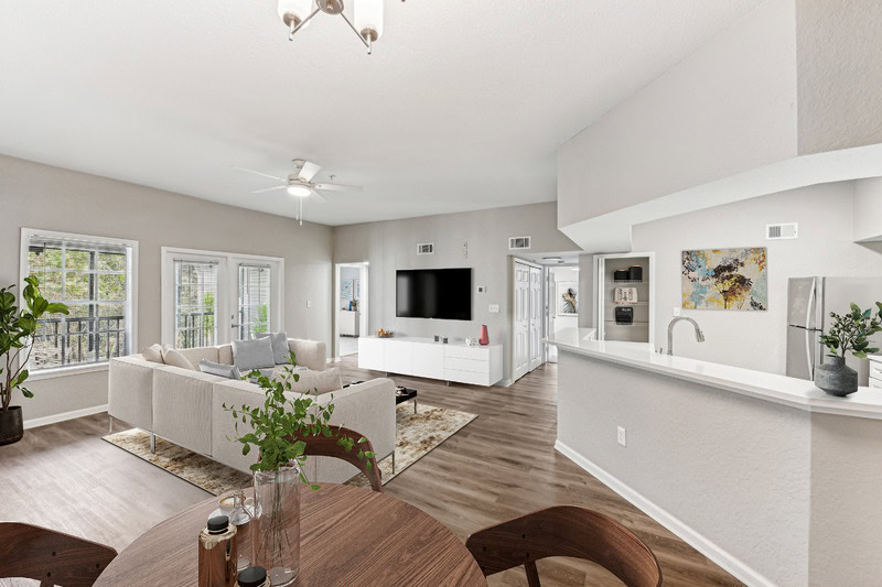 Open-concept apartment living and dining area with breakfast bar, wood-style flooring, and neutral finishes at The Domain.