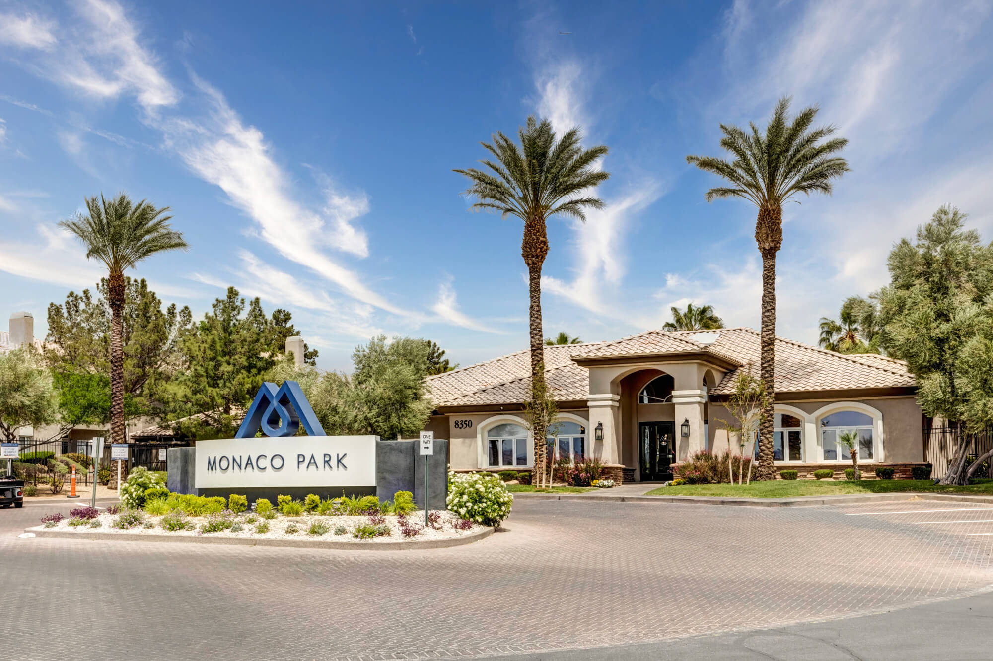 Monaco Park entrance sign and leasing office building with palm trees at the apartment community.