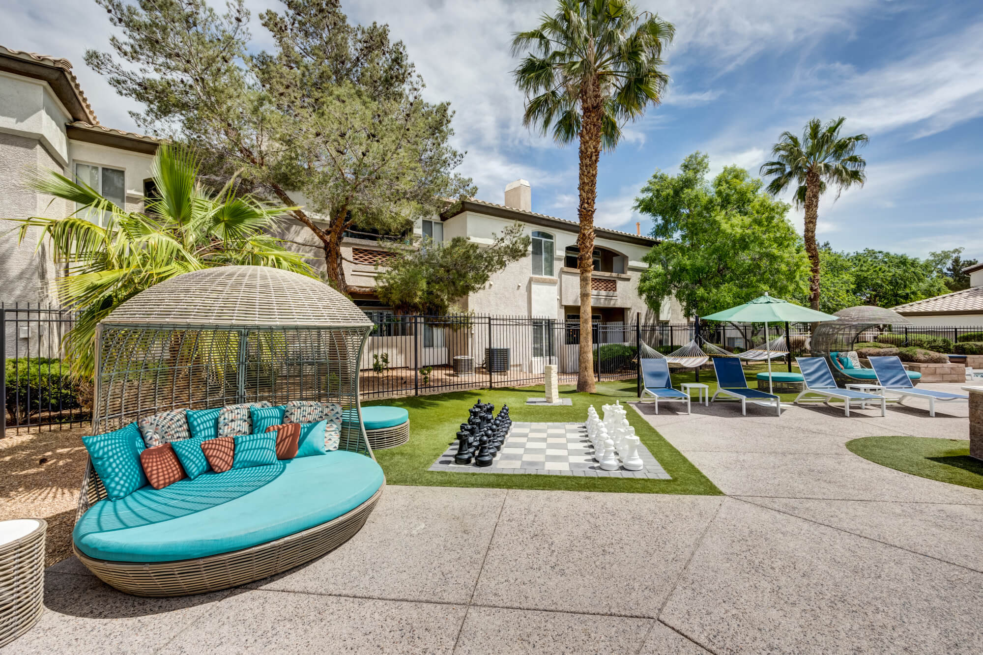 Outdoor lounge area with daybeds, hammocks, lounge chairs, and oversized chess at Monaco Park Apartments.