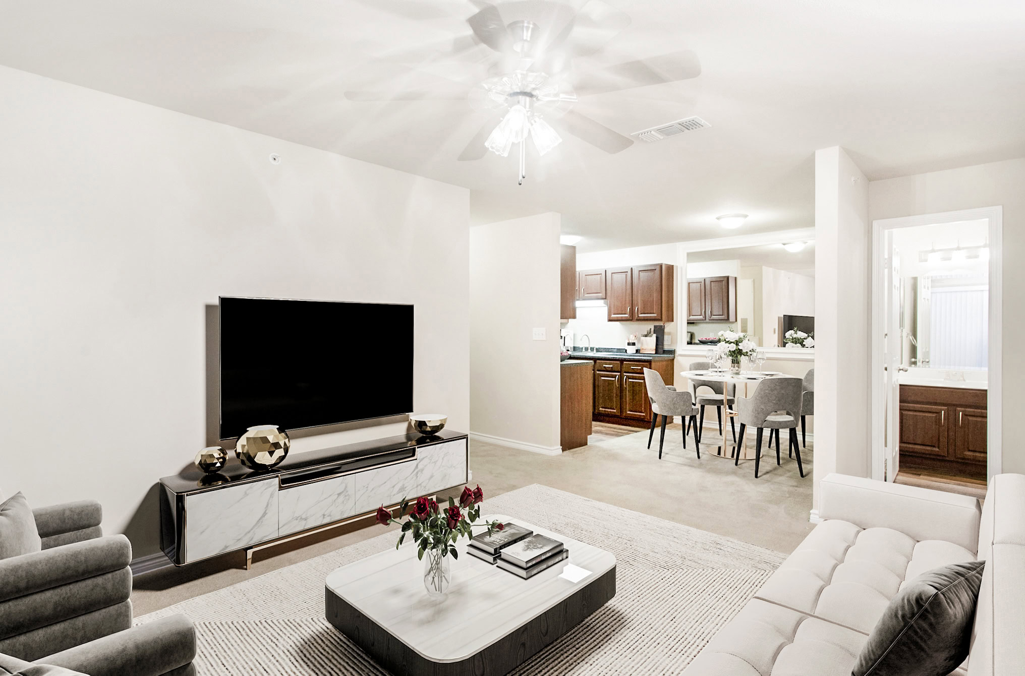 Modern living room in a Mckinney Texas apartment featuring neutral décor, carpeted flooring, and an open dining area with dark wood kitchen cabinetry.