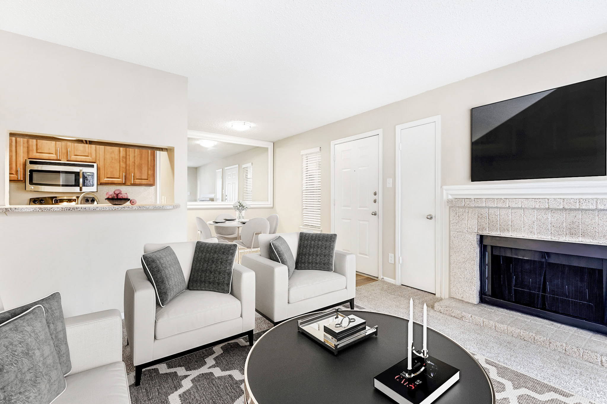 Bright living room in a Mckinney Texas apartment featuring a modern fireplace, neutral décor, and open access to the dining area and kitchen