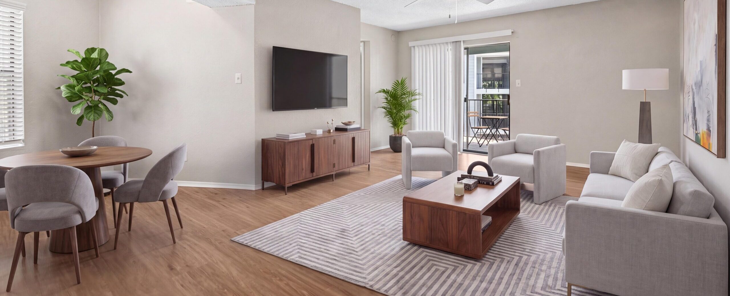 Spacious living room with hardwood plank flooring, ample sunlight, and ceiling fan.