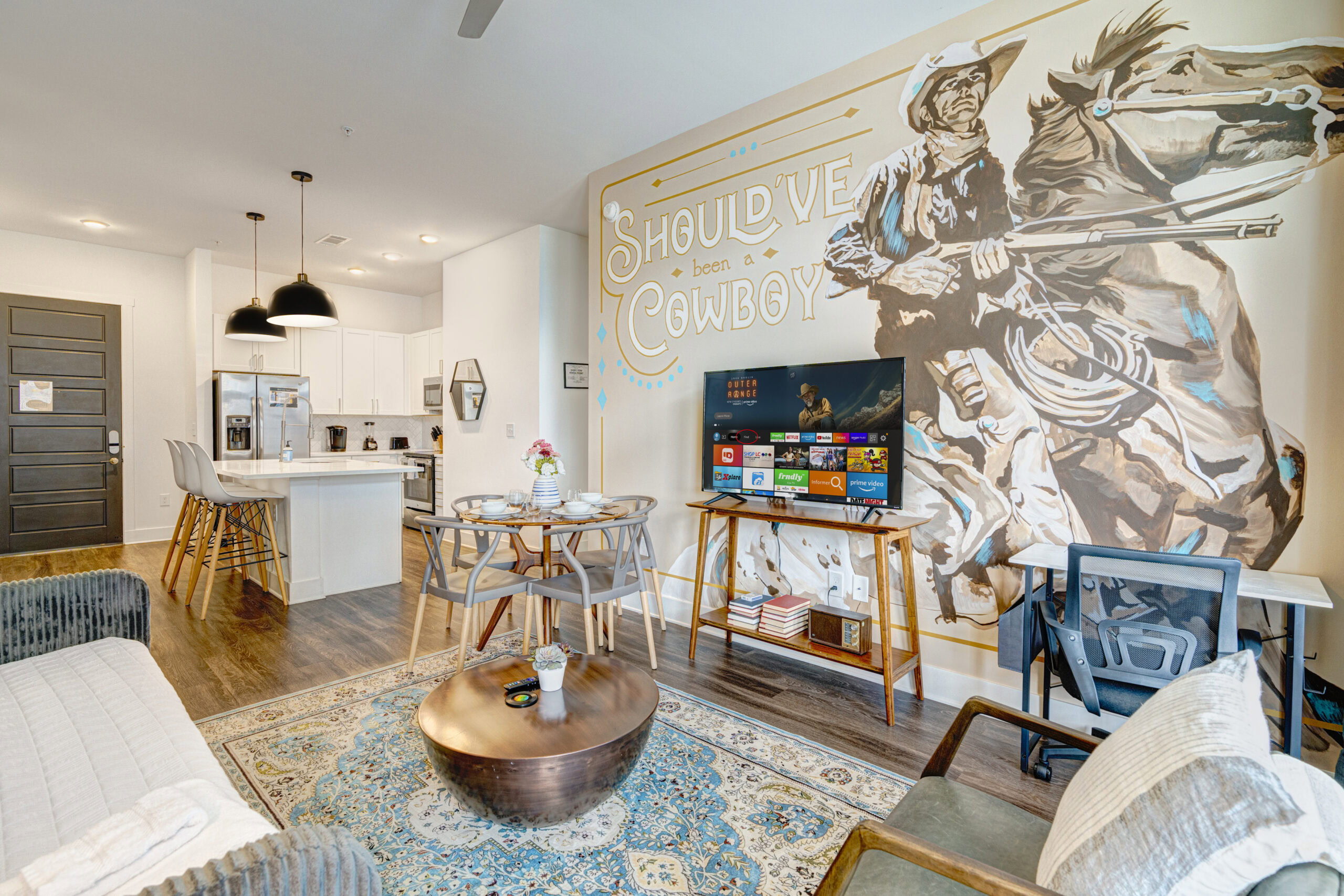 Spacious living room at LyvWell Apartments with modern decor, a large mural of a cowboy, and a cozy seating area.