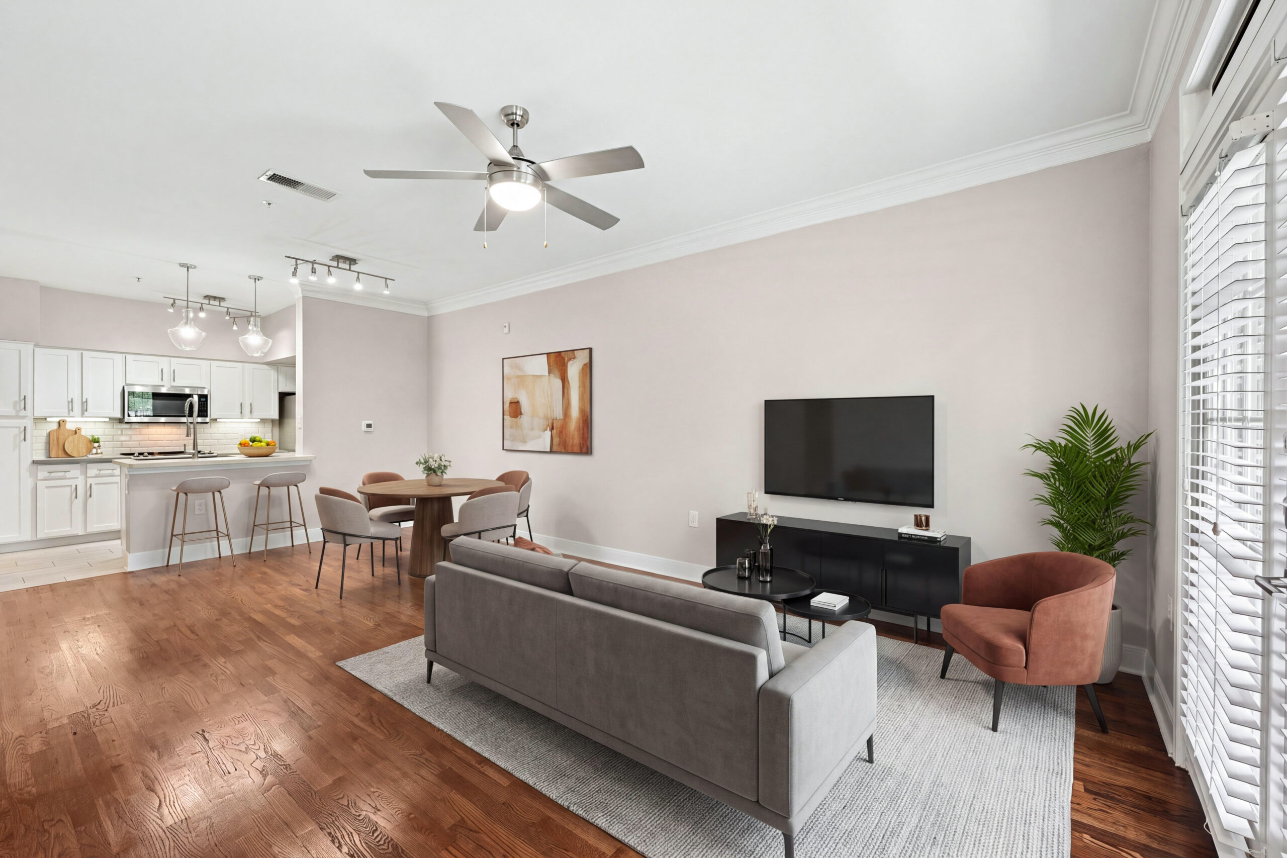 Open-concept living and dining area at Village on Memorial featuring hardwood flooring, a ceiling fan and a modern kitchen with breakfast bar seating.