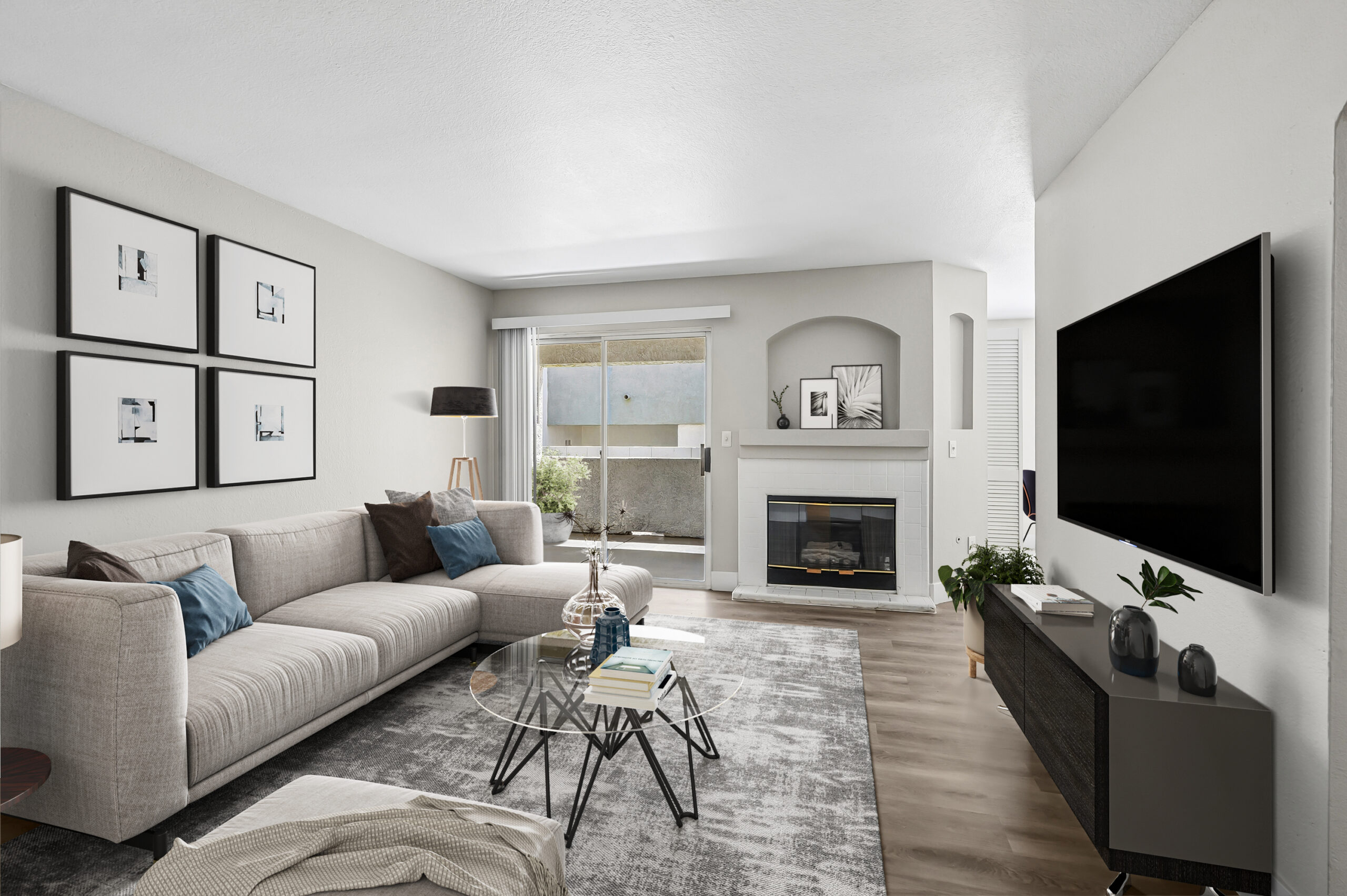 Furnished Vintage Pointe apartment living room with a fireplace, sectional sofa, wood-style flooring, and sliding glass doors leading to a private patio.